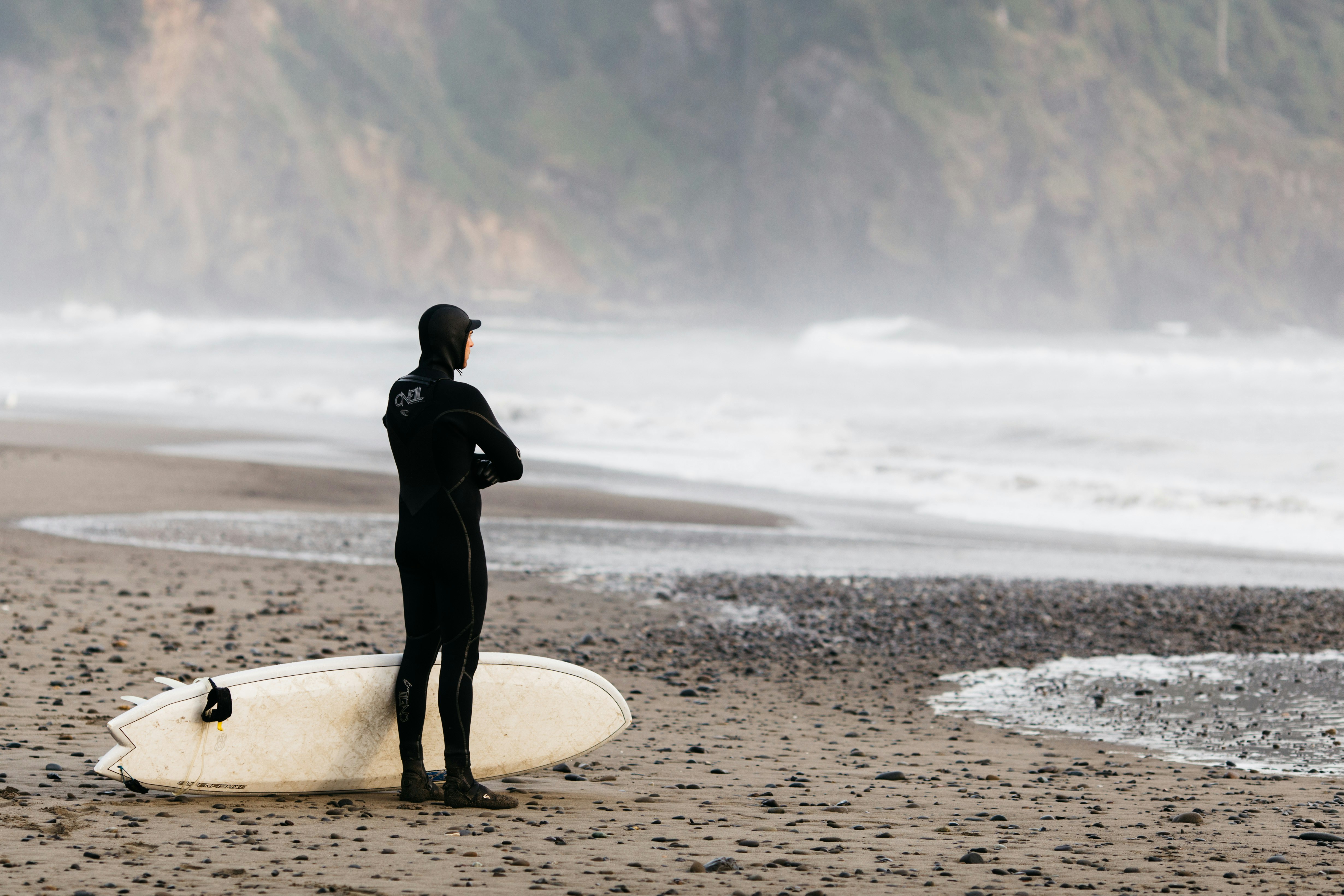 man standing on shoreline with surfboard